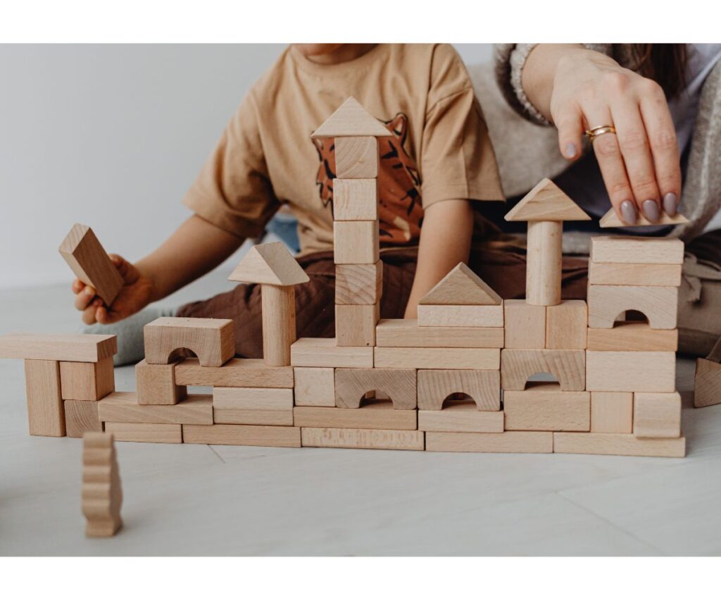 kid and mom playing with wooden blocks in a neat row.