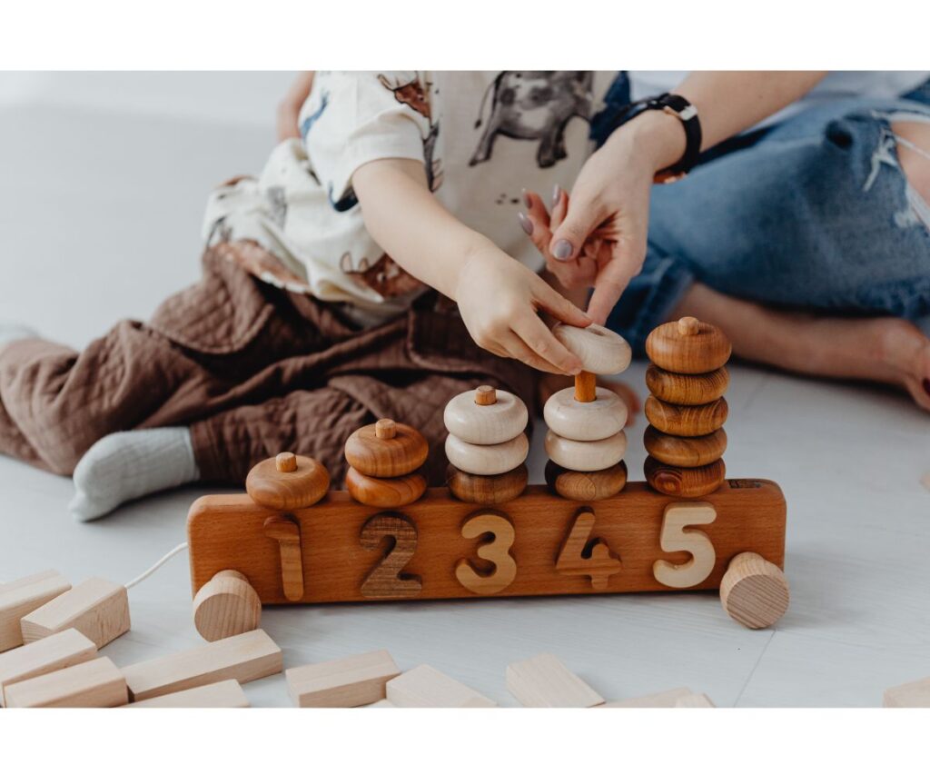 A kid playing with a wooden counting toy.