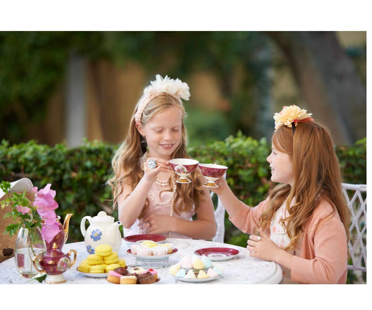 two young girls enjoying an outdoor tea party.